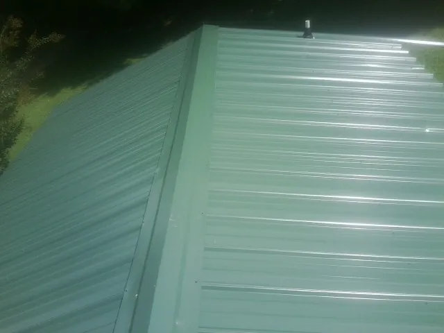 New green metal panels meeting at the ridge of a roof — Flat Roof Repair work by our crew in Maidens