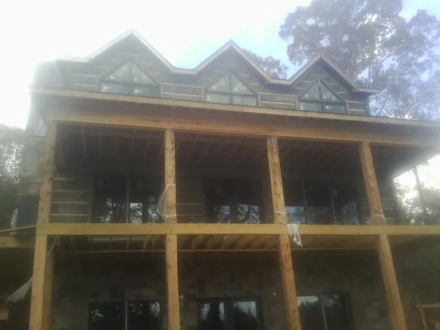 Dormers and porch framing on a large log home under construction — Roof Coating work by our crew in Maidens