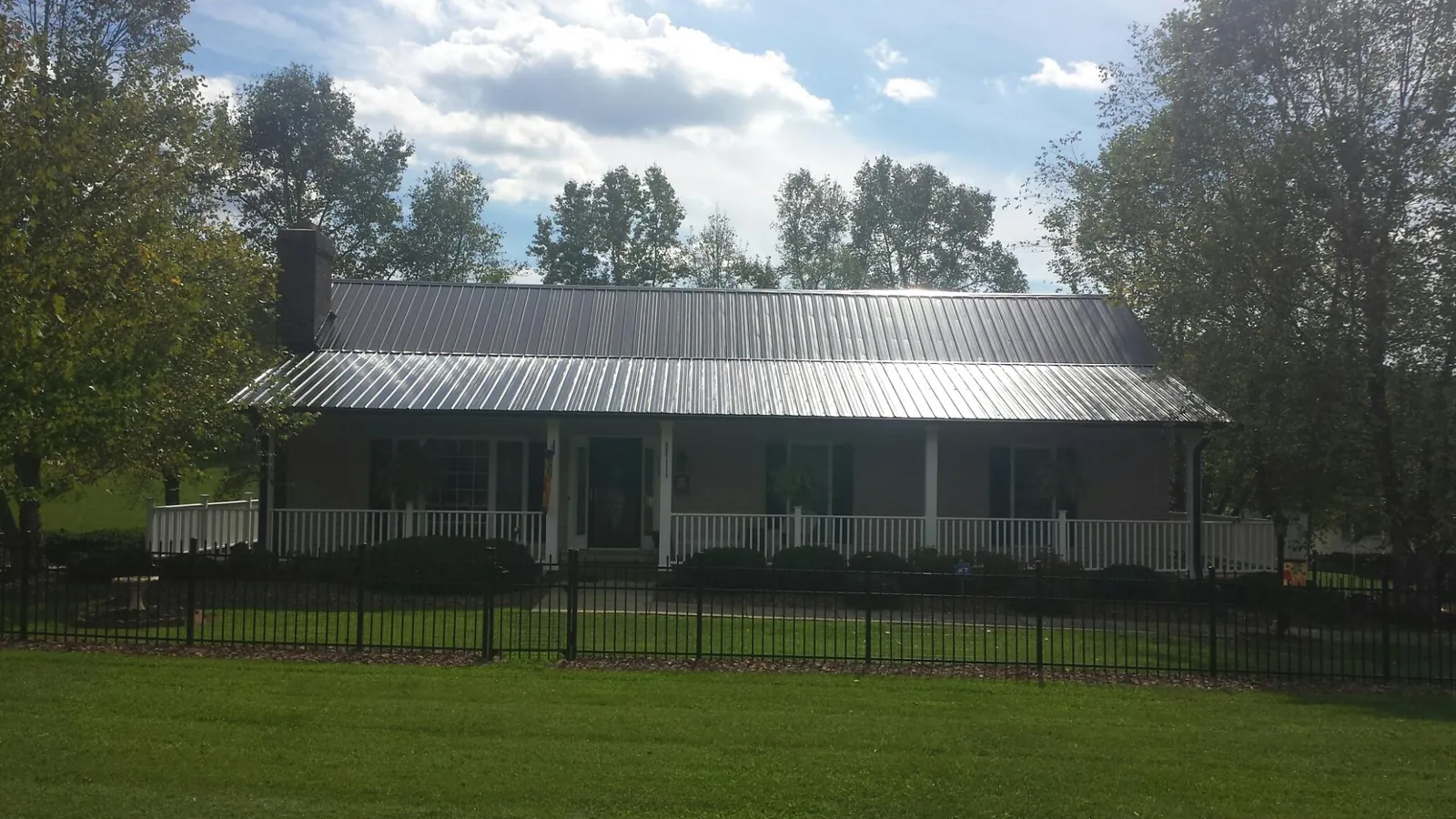 Gray metal roof on a brick ranch with a full width front porch — Gutter Guard Installation work by our crew in Maidens