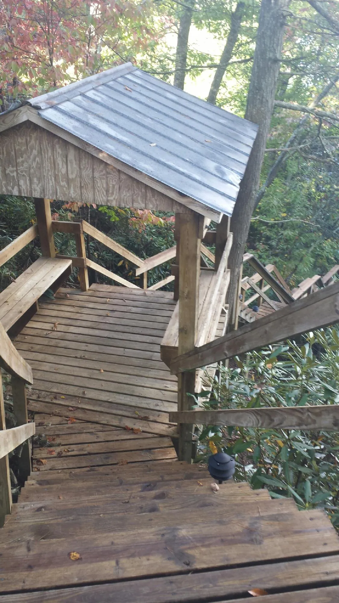 Metal roofed shelter over wooden steps on a wooded walkway — Skylight Repair & Installation work by our crew in Maidens
