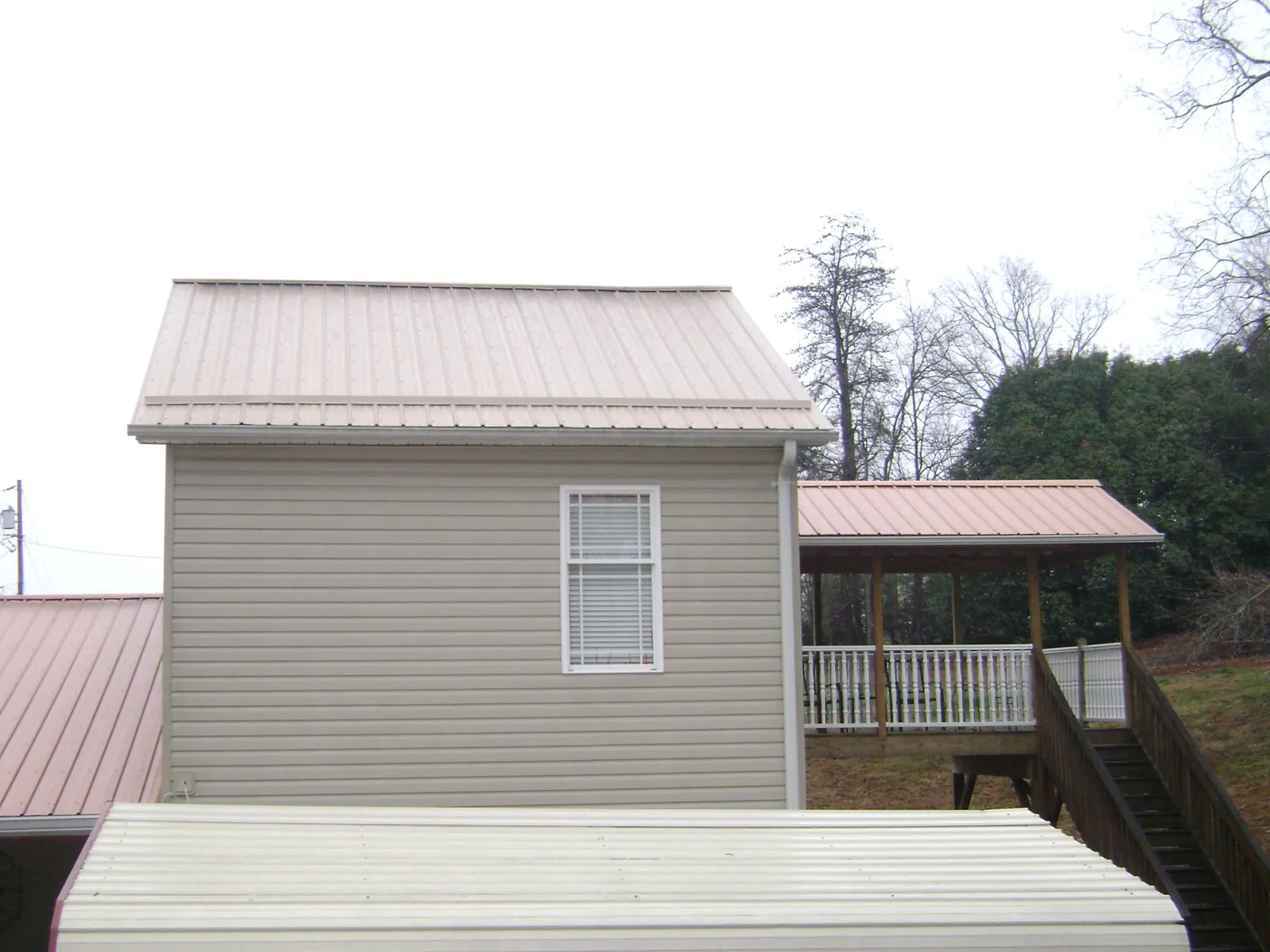 Tan metal roofs on a two story addition and attached porch, from a Roof Replacement job in Maidens