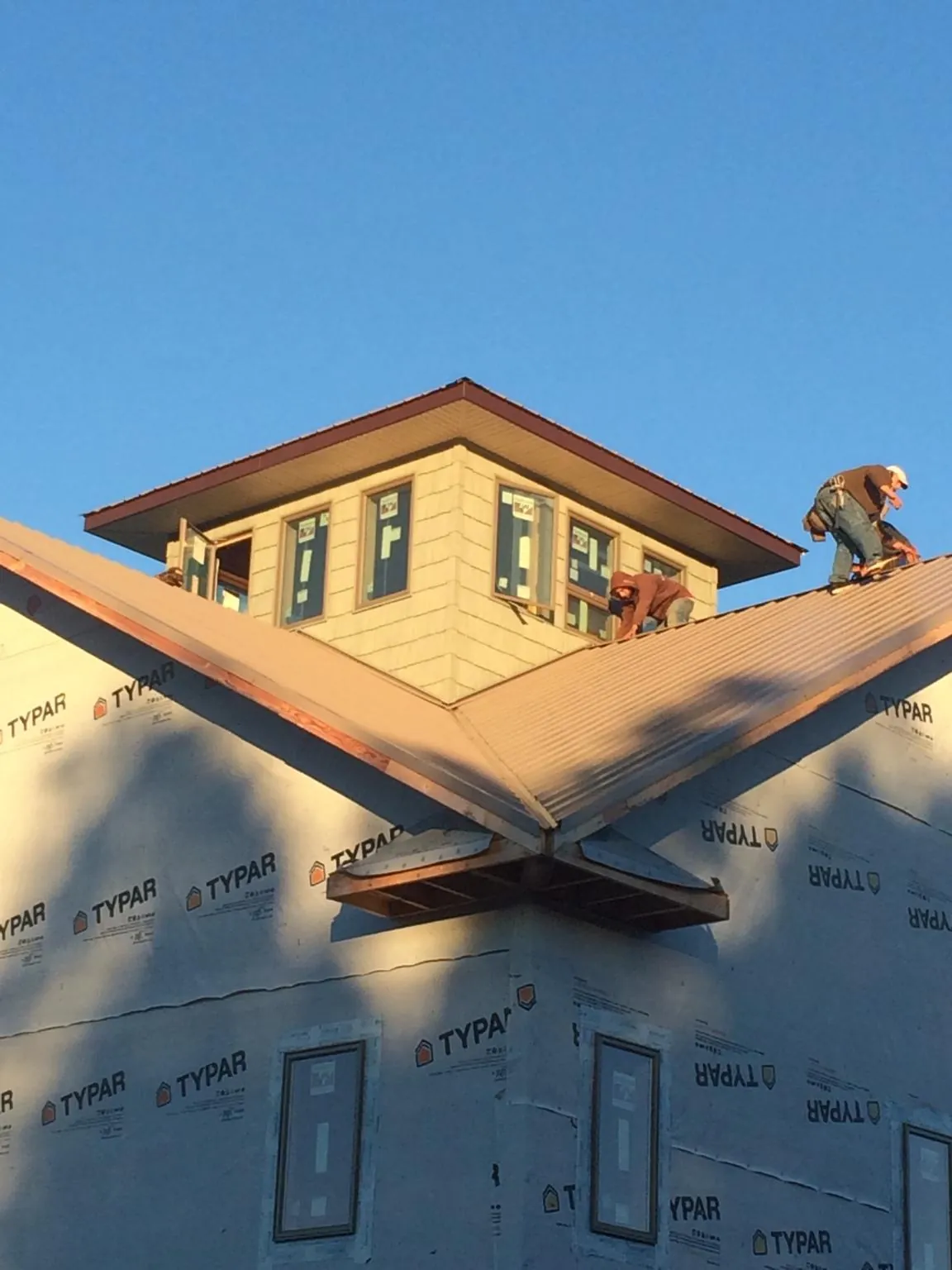 Roofers working around a rooftop cupola on a new metal roof at sunset — Roof Waterproofing in Maidens by Roofing Brothers